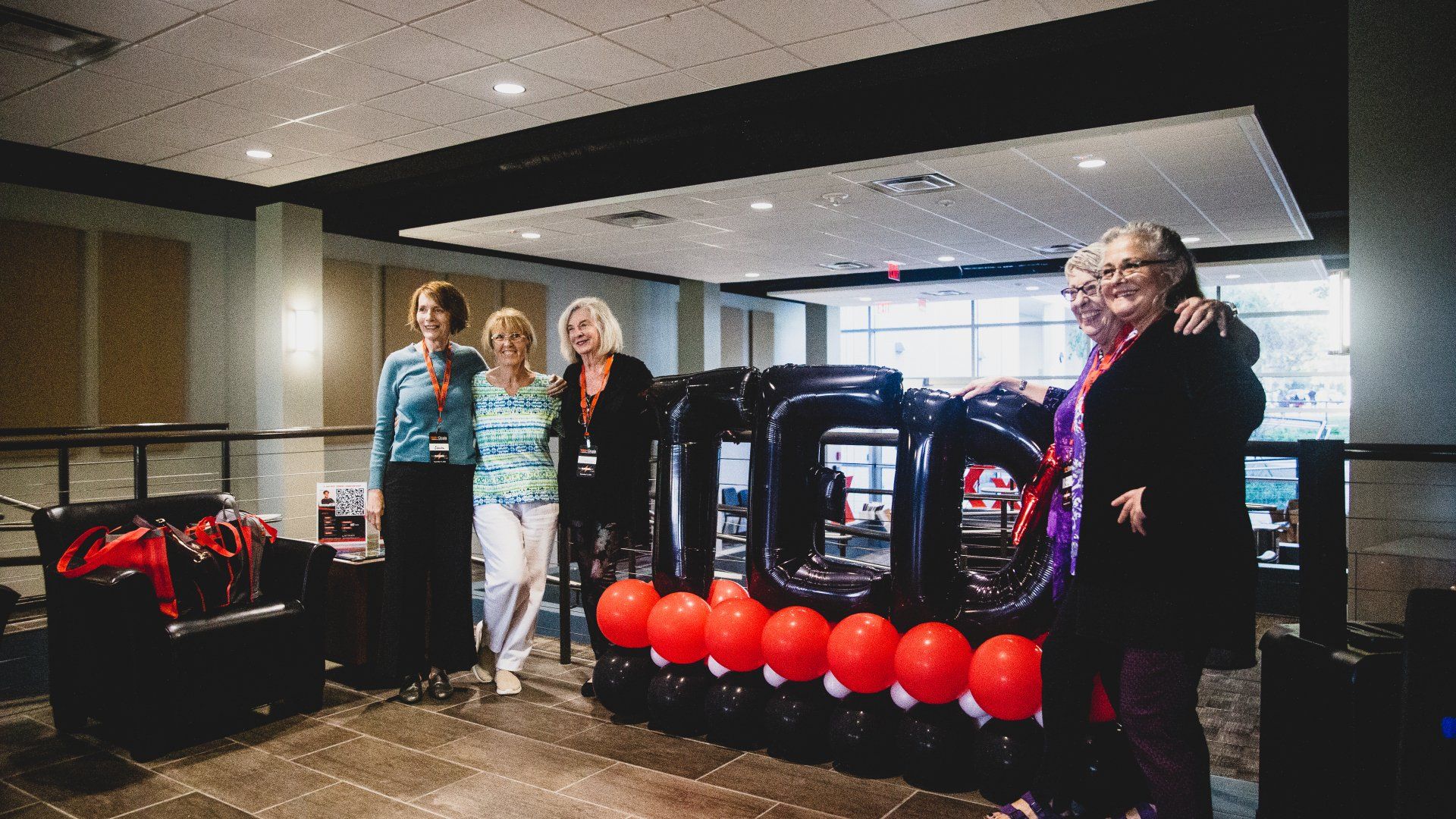 A group of women are standing in front of a sign made of balloons.