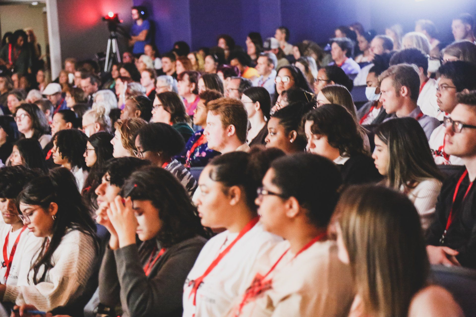 A large group of people are sitting in an auditorium watching a presentation.