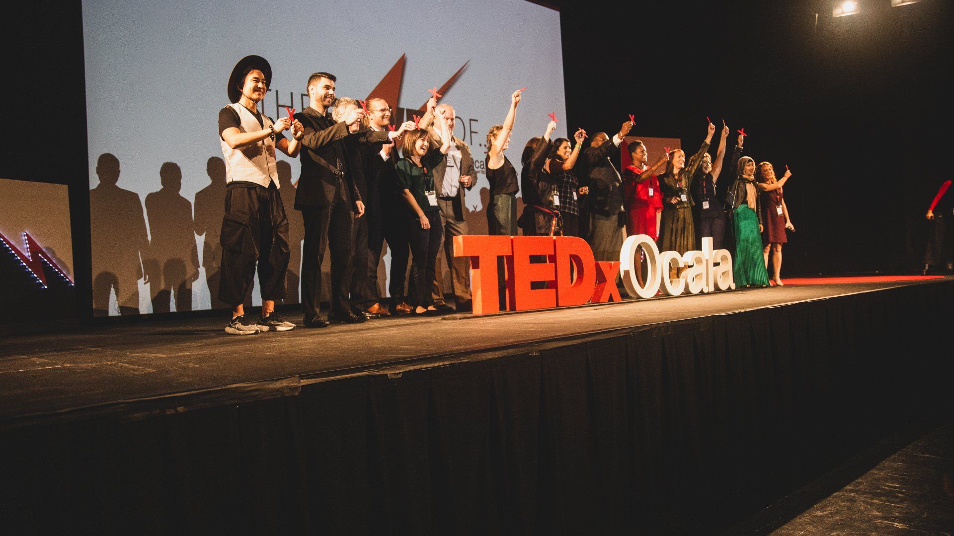 A group of people are standing on a stage in front of a ted talk sign.