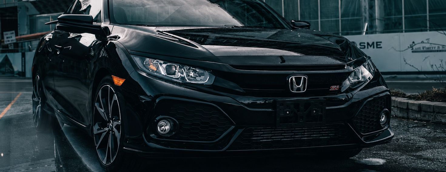 Black Honda Civic in the rain, front view on a wet street at night
