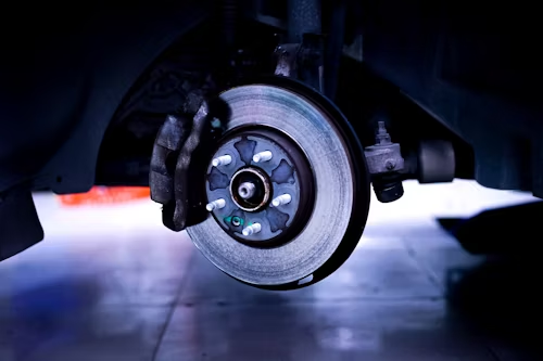 Car brake disc and caliper, close-up, indoors.