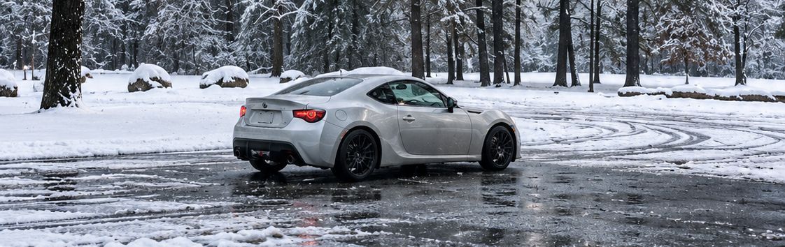 Silver sports car parked on a snowy road in a winter forest