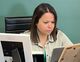 A woman is sitting at a desk looking at a tablet.