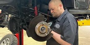 A man is working on a brake on a truck in a garage.