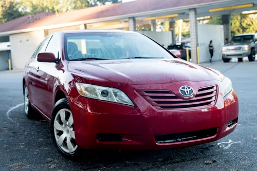 Red Toyota sedan parked outside a service station at dusk