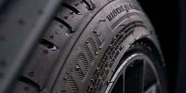 A close up of a car tire with water drops on it.