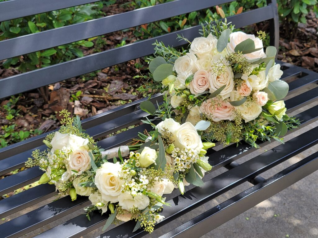 Two bouquets of flowers are sitting on a black bench.