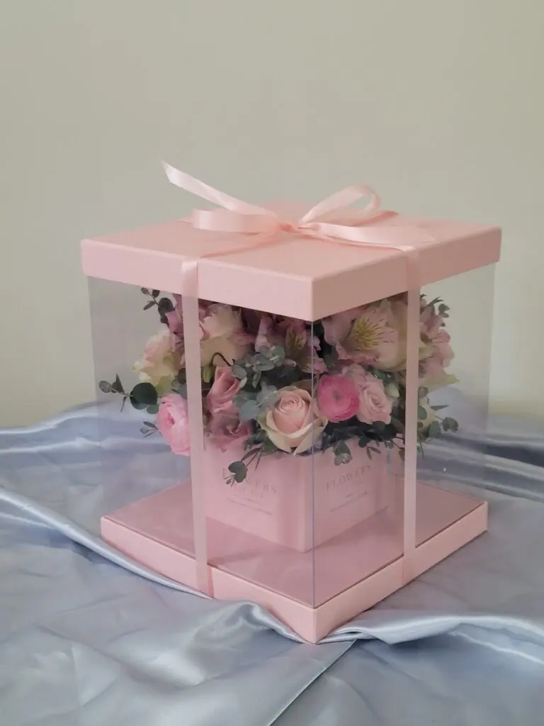 A pink box filled with flowers is sitting on a table.