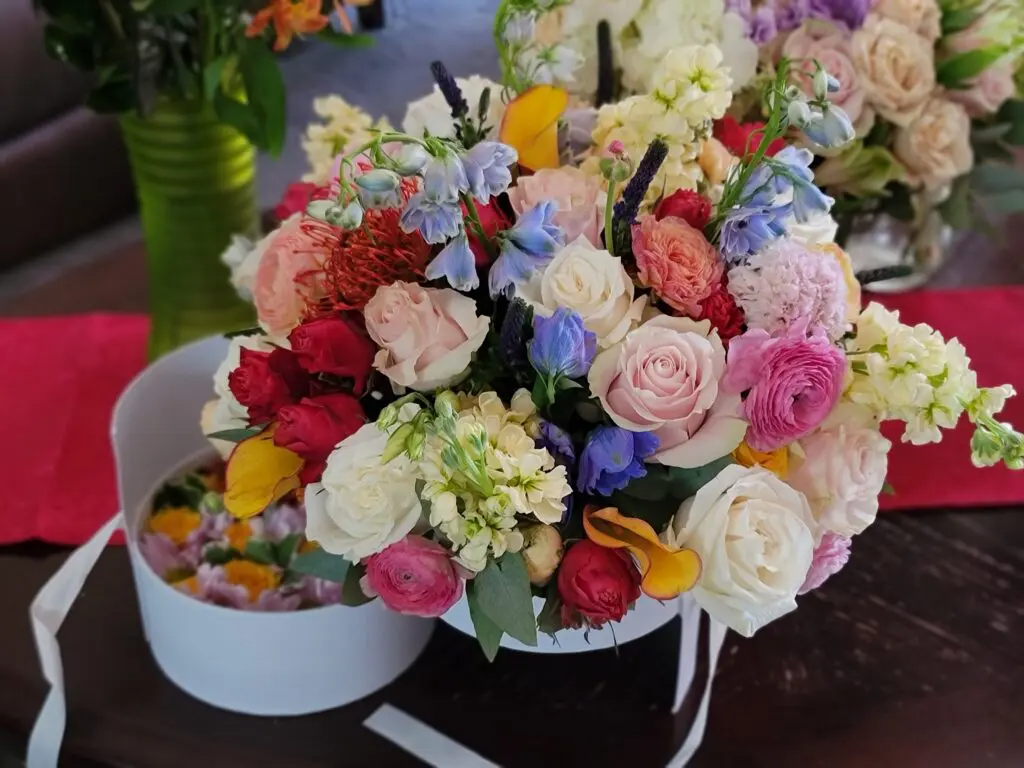A bouquet of flowers in a white box on a table.