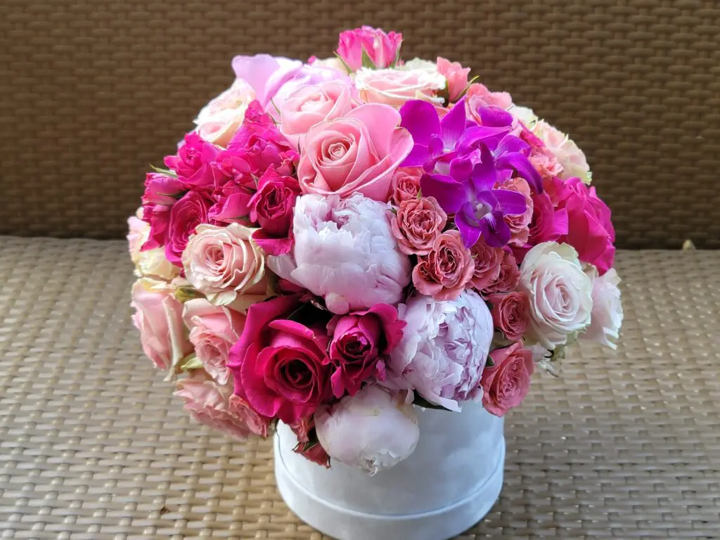 A white box filled with pink and white flowers on a table.
