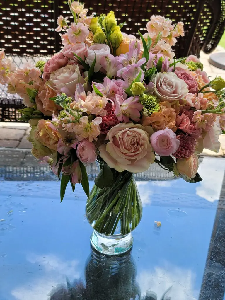 A vase filled with pink and yellow flowers is sitting on a table.