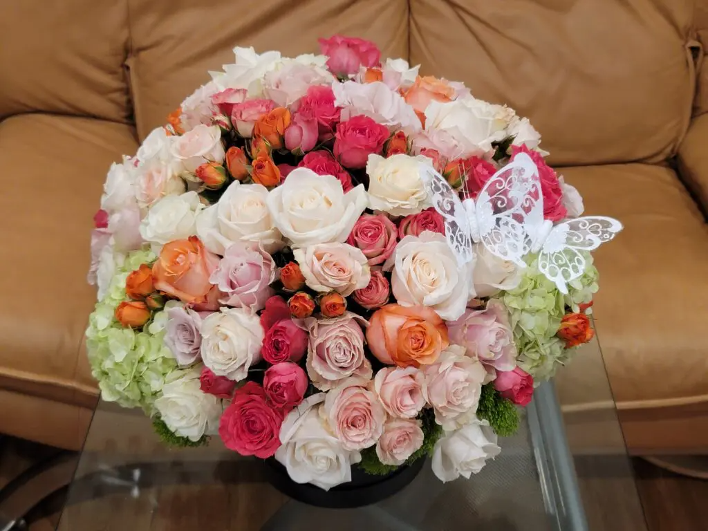 A vase of flowers with a butterfly on top of it