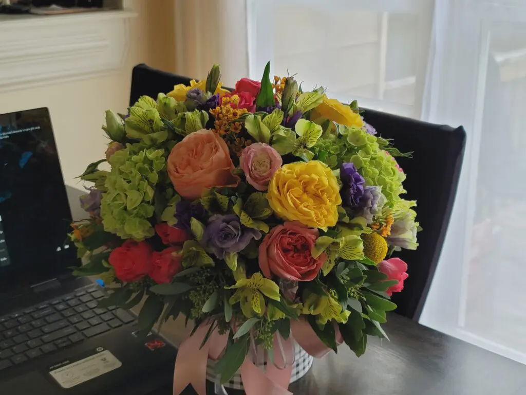 A bouquet of flowers is sitting on a table next to a laptop.