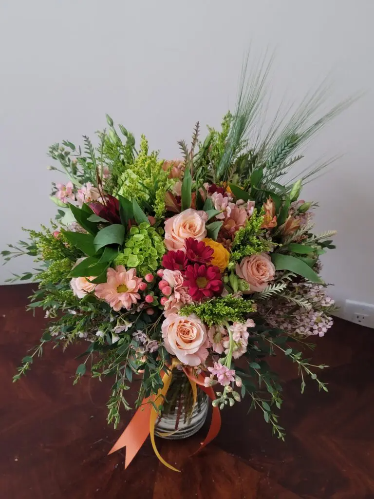 A vase filled with flowers is sitting on a wooden table.