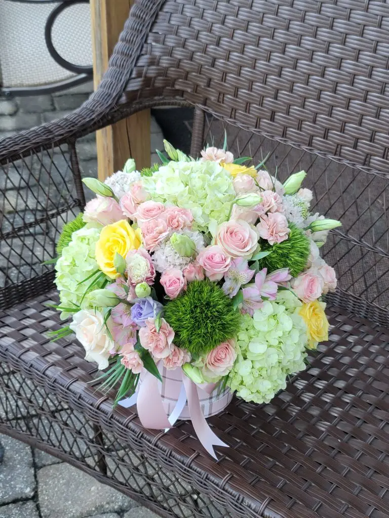 A bouquet of flowers is sitting on a wicker bench.