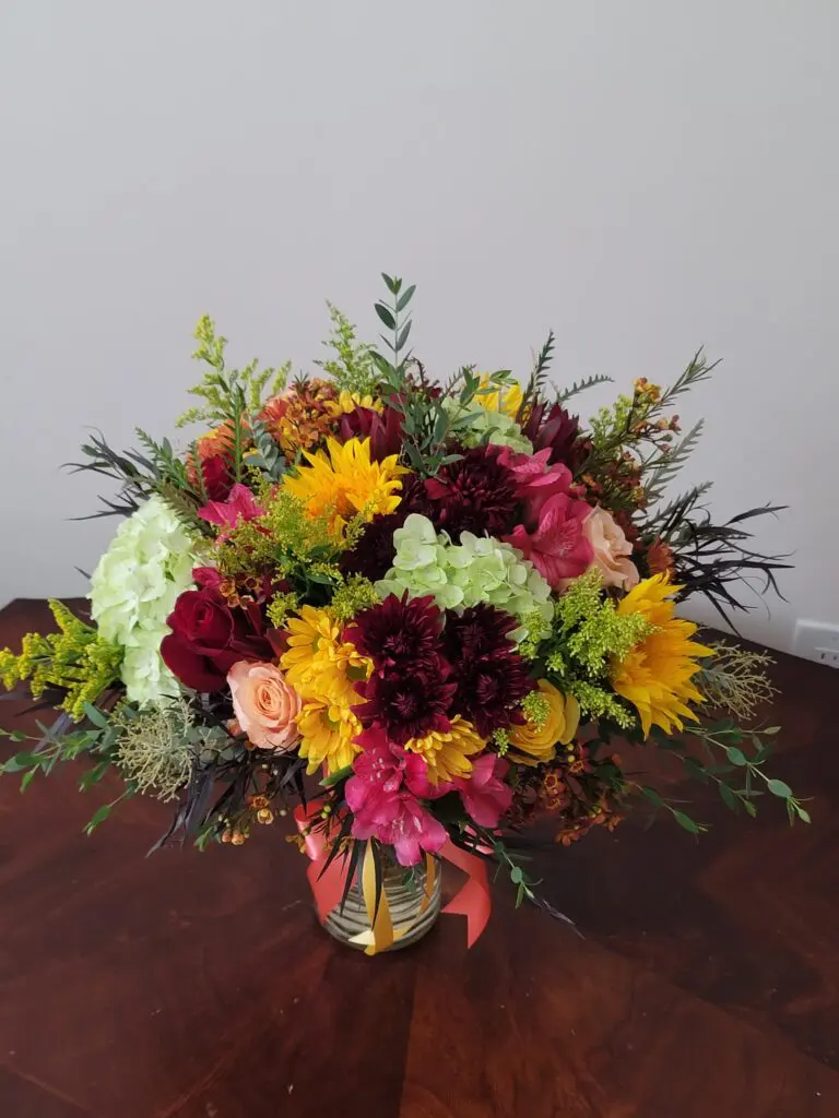 A vase filled with flowers is sitting on a wooden table.