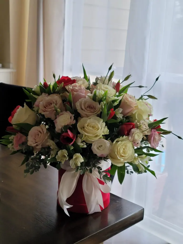 A vase filled with flowers is sitting on a table in front of a window.