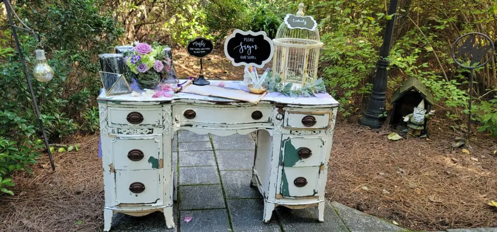 A white desk with drawers and a bird cage on top of it.