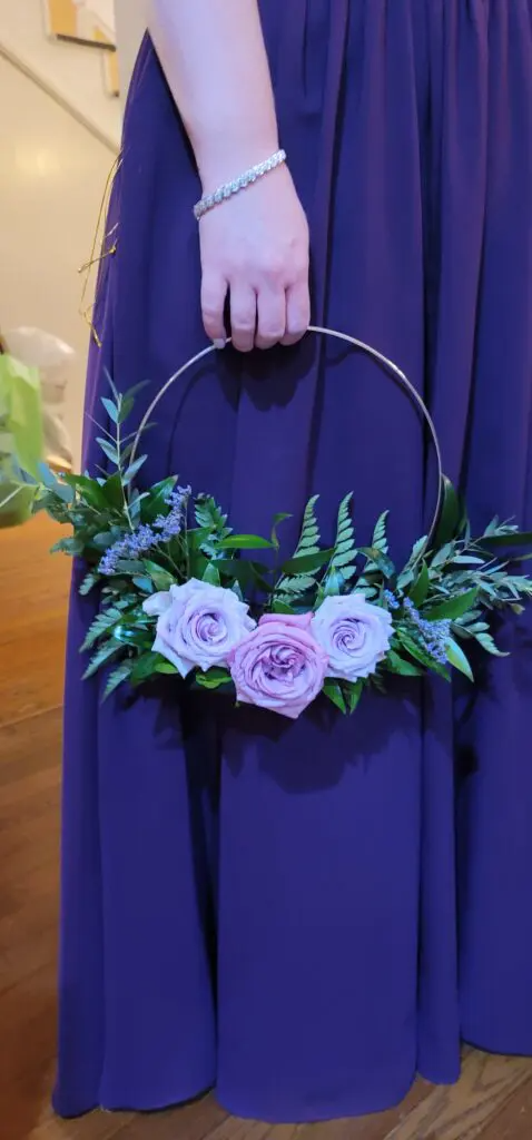 A woman in a purple dress is holding a basket of flowers.