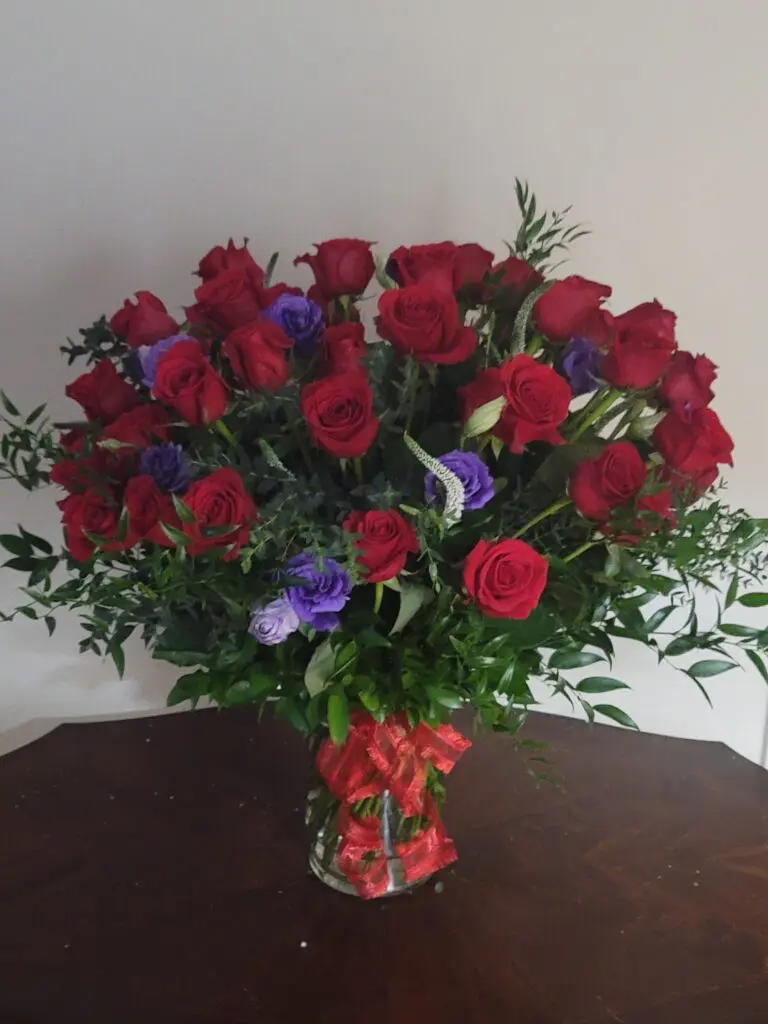 A vase filled with red and purple roses is sitting on a table.