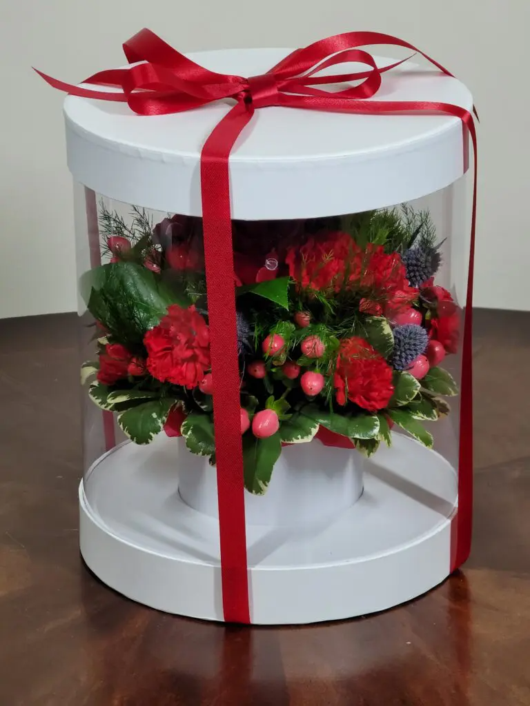 A white box filled with red flowers and a red ribbon