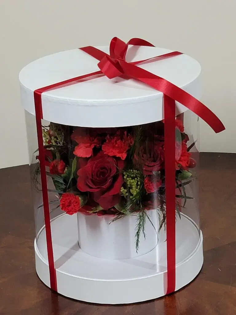 A white box filled with red flowers and a red ribbon.