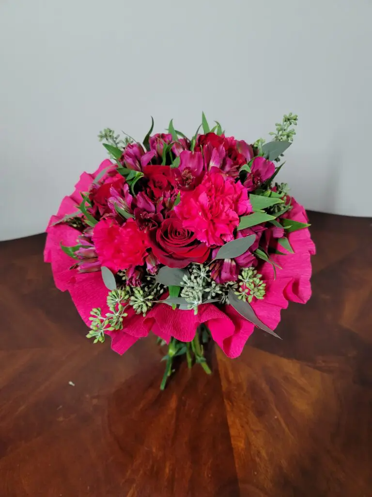 A bouquet of pink flowers is sitting on a wooden table.