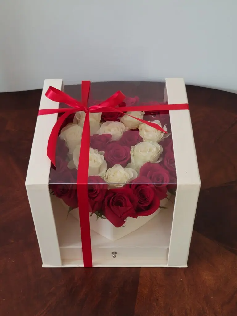 A box of red and white roses with a red ribbon