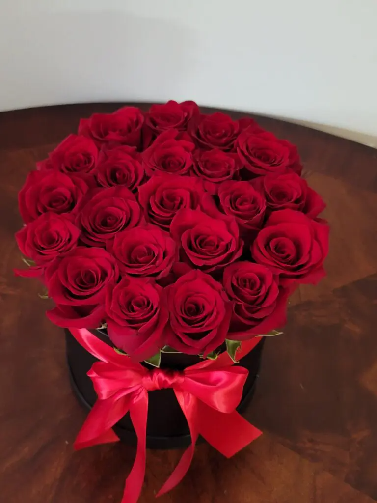 A black box filled with red roses with a red bow