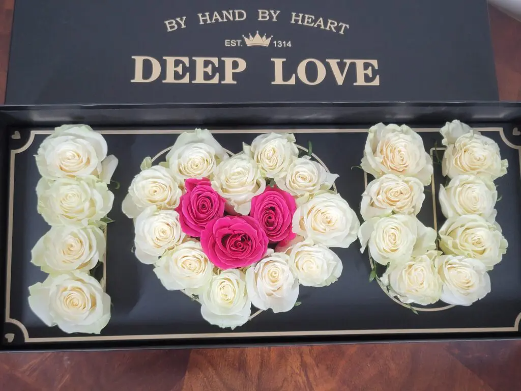 A box filled with white roses and pink roses that says deep love
