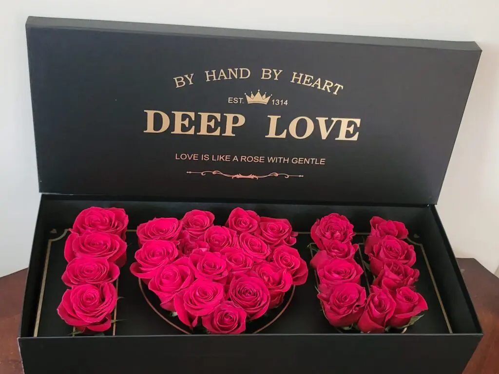 A black box filled with red roses that says deep love