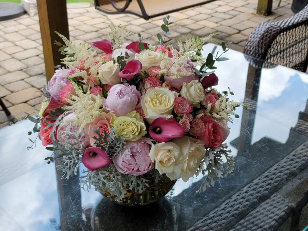 A vase filled with pink and white flowers sits on a glass table.