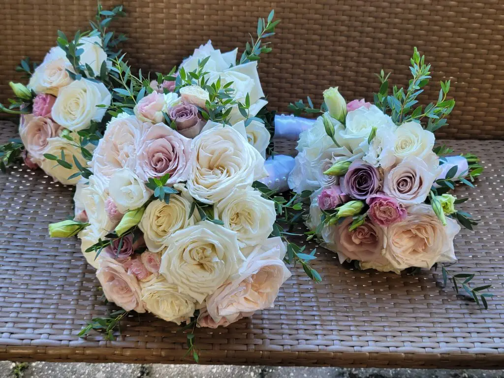 Two bouquets of flowers are sitting on a wicker bench.
