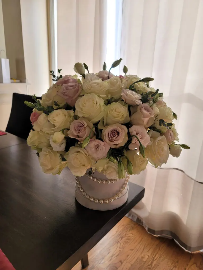 A vase filled with white roses and pink roses is sitting on a table.