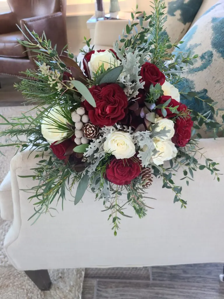 A bouquet of red and white flowers is sitting on a chair in a living room.