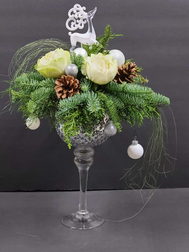 A glass vase filled with flowers and pine cones on a table.