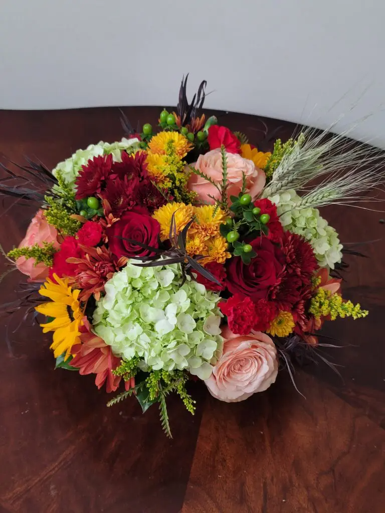 A bouquet of flowers is sitting on a wooden table.