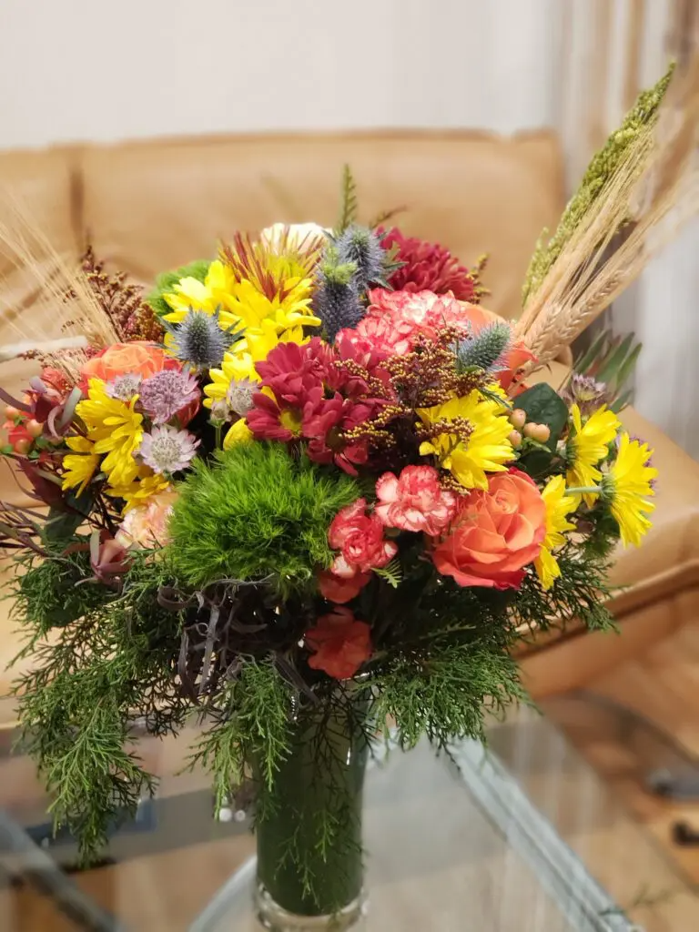 A vase filled with flowers is sitting on a glass table.