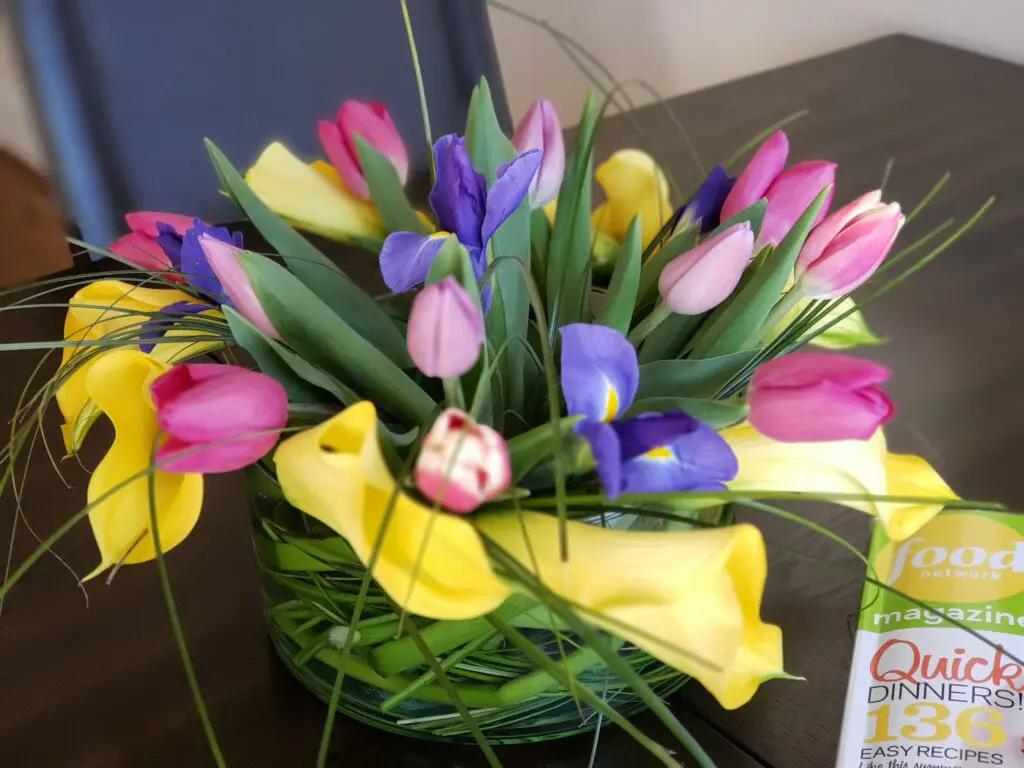 A vase filled with pink and yellow flowers sits on a table