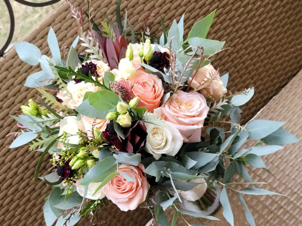 A bouquet of flowers is sitting on a wicker chair.
