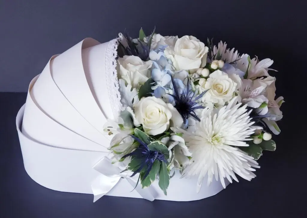 A white carriage filled with white flowers on a table.