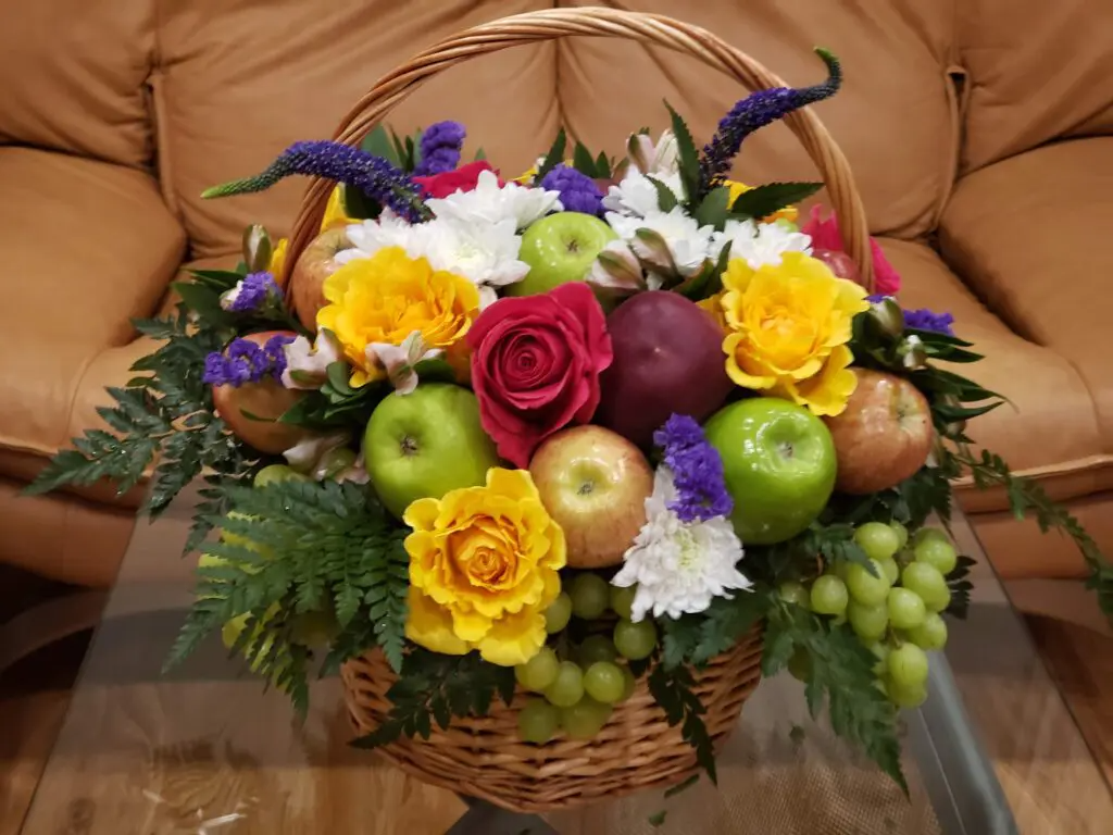 A basket filled with fruit and flowers is on a table