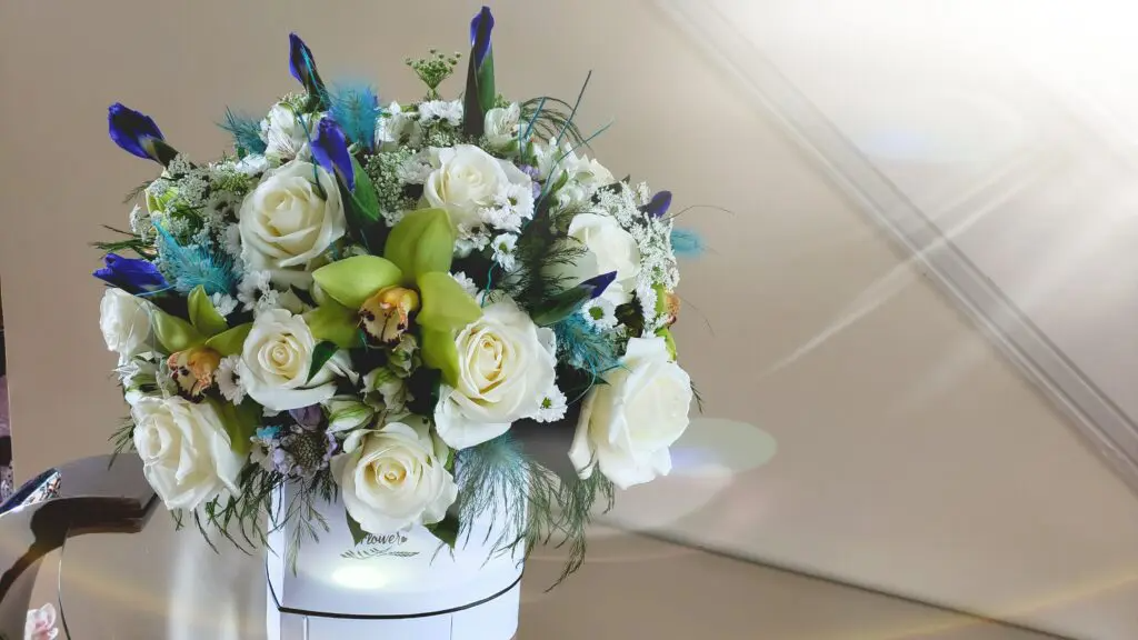 A white box filled with white roses and blue flowers.