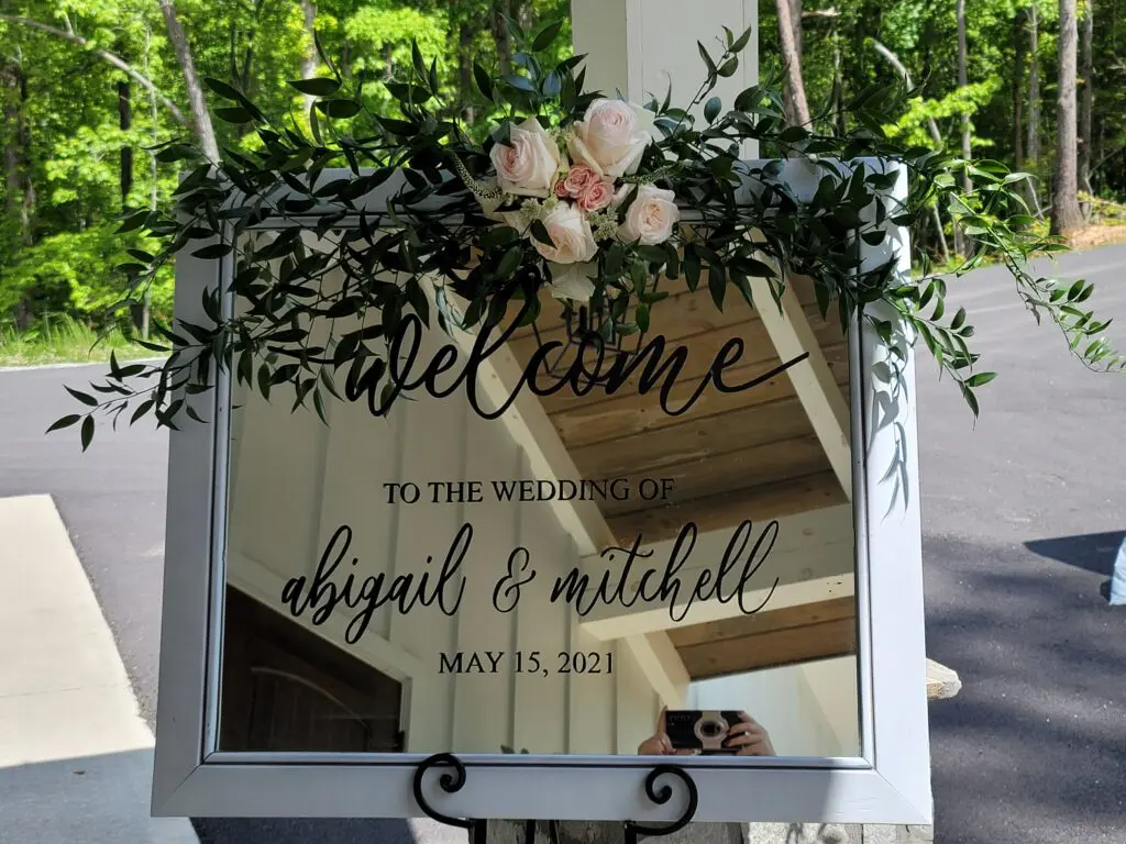 A welcome sign for a wedding is hanging on a mirror.