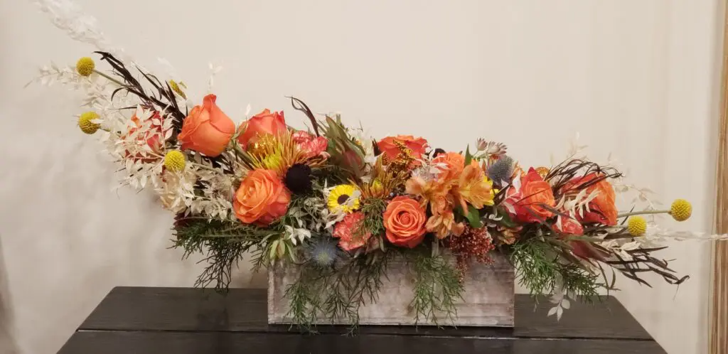A wooden box filled with flowers is sitting on a table.
