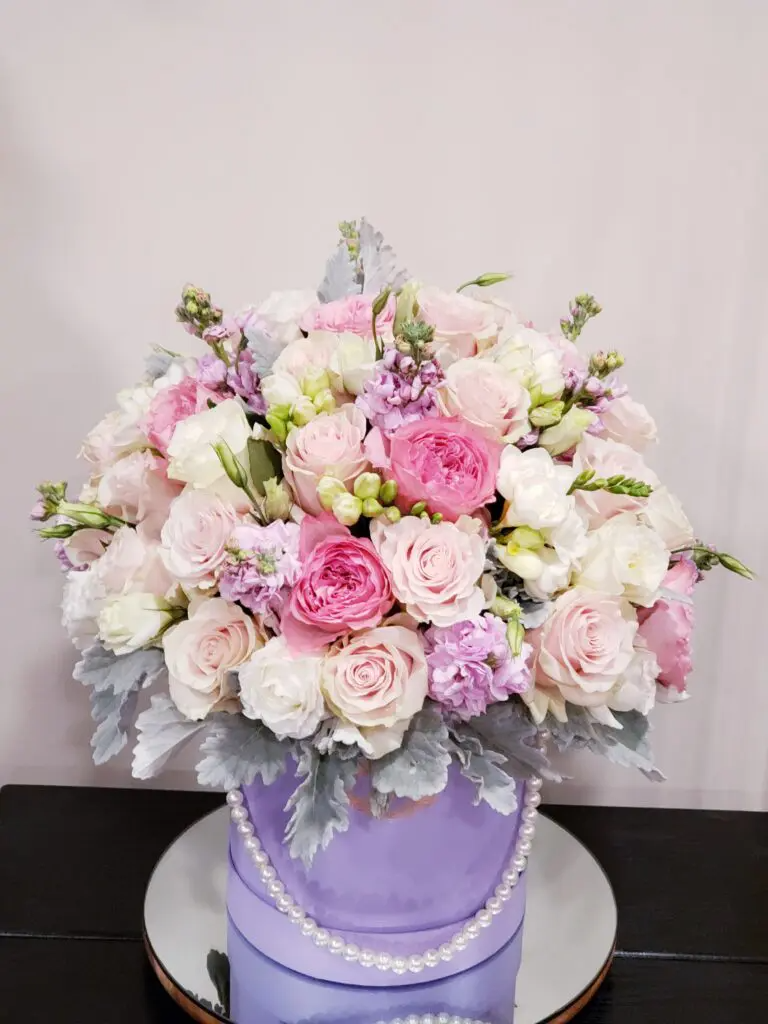 A purple box filled with pink and white flowers is sitting on a table.
