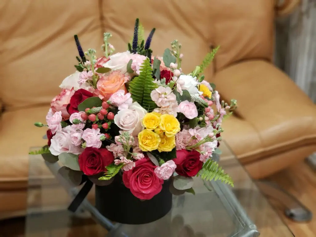 A vase filled with flowers is sitting on a glass table.