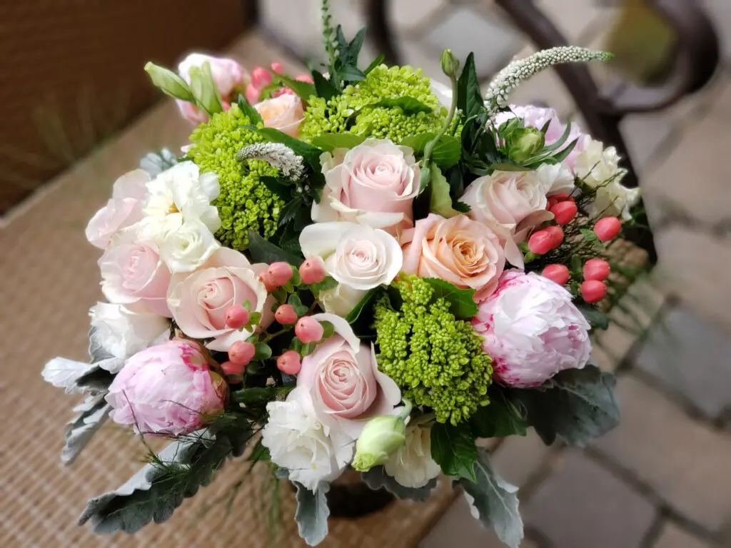 A vase filled with pink and white flowers is sitting on a chair.
