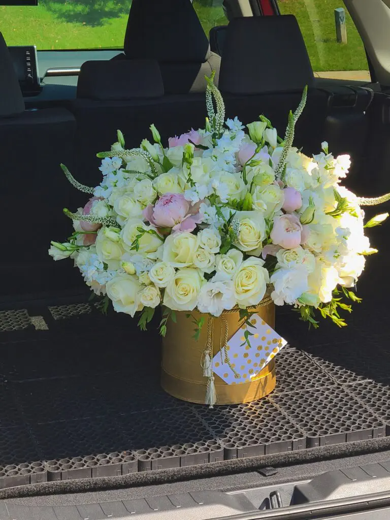 A large bouquet of white flowers is in the back of a car.