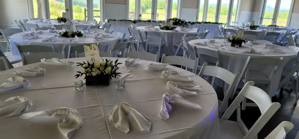 A room filled with tables and chairs set up for a wedding reception.